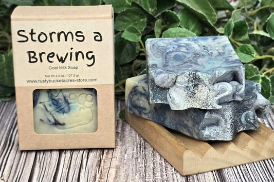 Bar of soap with 'Storms a Brewing' packaging on a wooden surface with greenery in the background