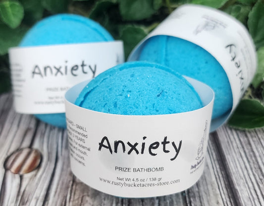 Blue bath bomb labeled 'Anxiety' with packaging on a wooden surface.