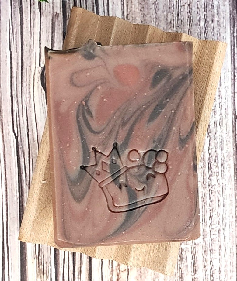 Marbled soap with a crown design on a wooden soap dish.