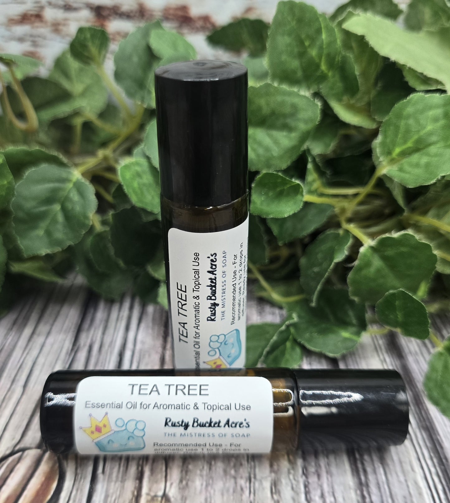 Two roll-on bottles of Tea Tree essential oil with a green leafy background