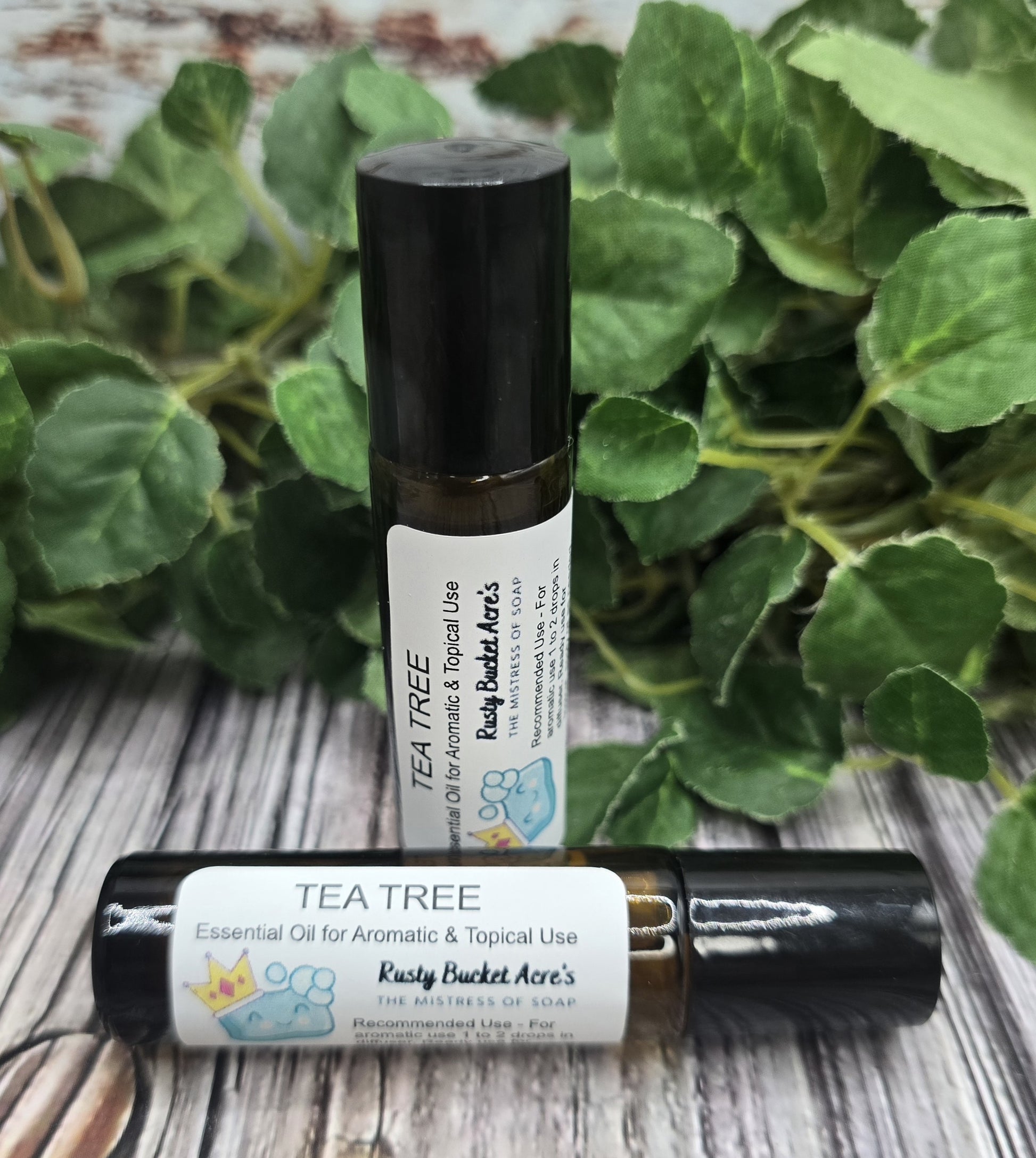 Two roll-on bottles of Tea Tree essential oil with a green leafy background