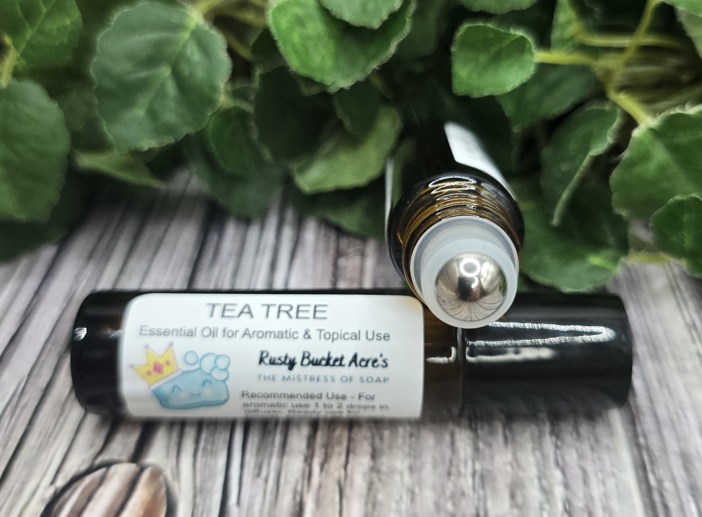 Tea tree essential oil roller bottle with a white label on a wooden surface with green leaves in the background