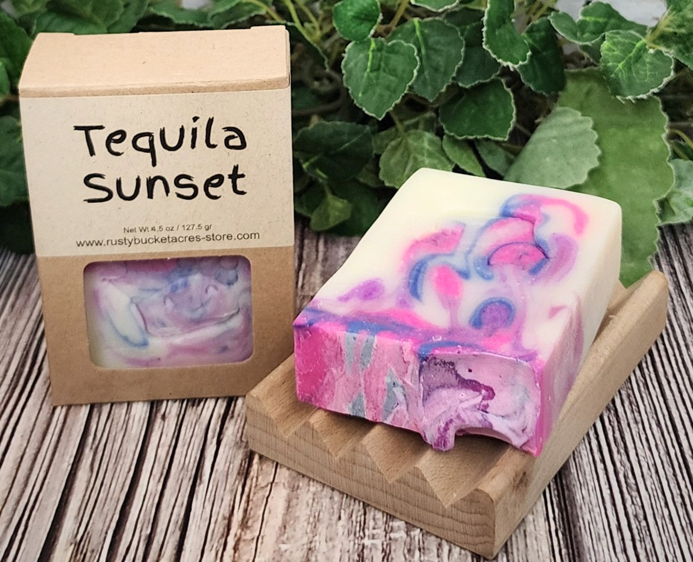 Colorful soap bar with 'Tequila Sunset' packaging on a wooden surface with green leaves in the background