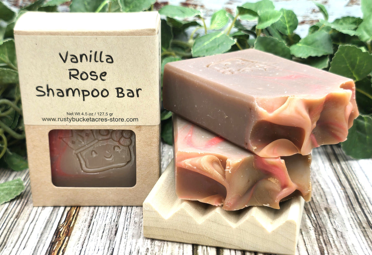 Vanilla Rose shampoo bar with packaging on a wooden surface with greenery in the background