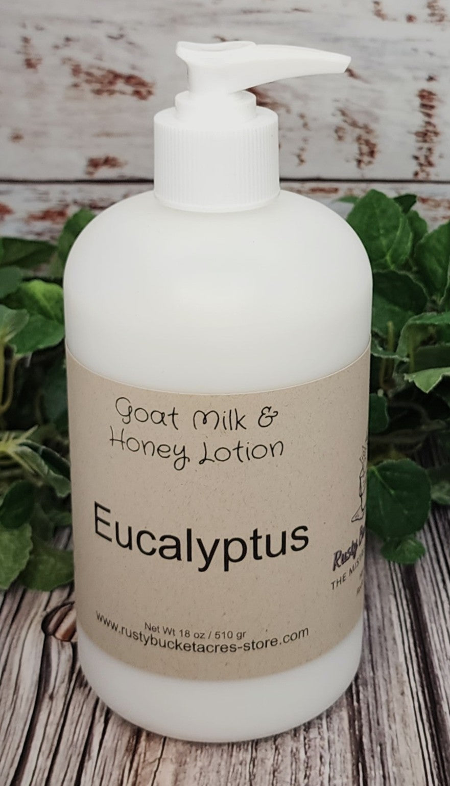 Bottle of Eucalyptus goat milk and honey lotion on a wooden surface with greenery in the background.