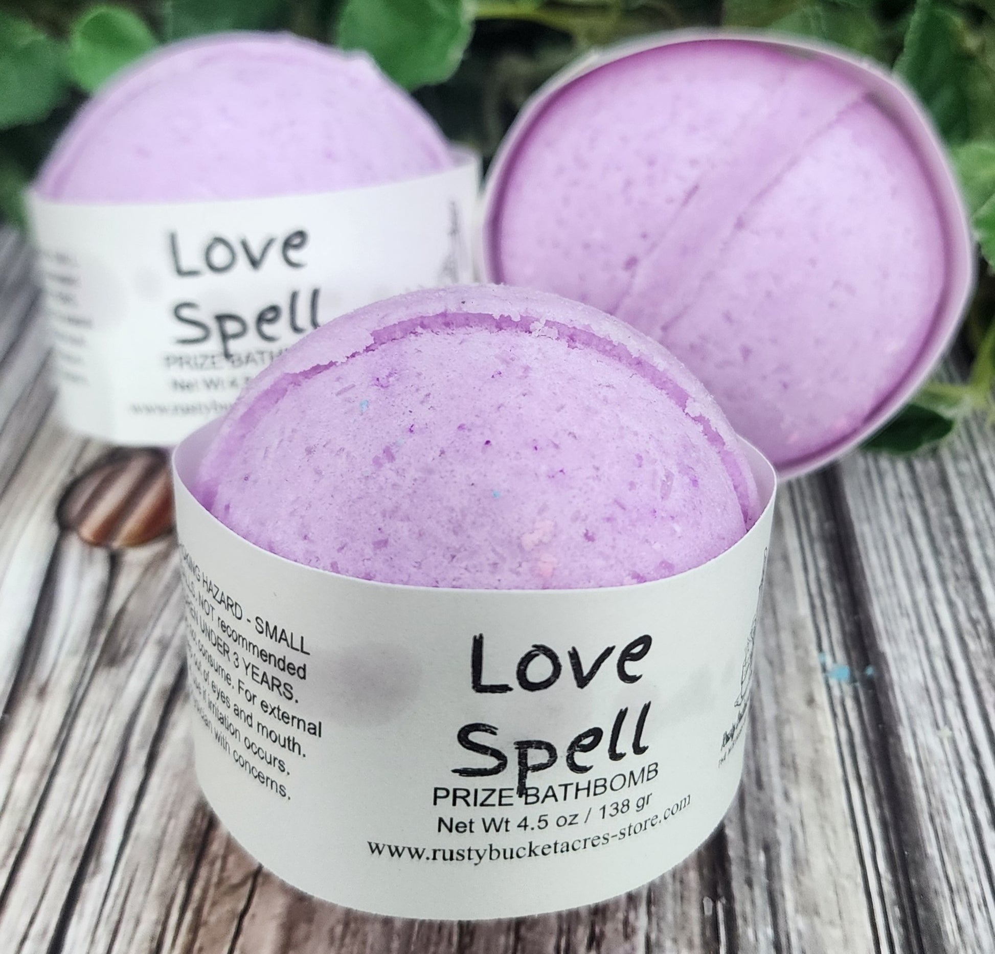 Purple bath bomb with 'Love Spell' label on a wooden surface