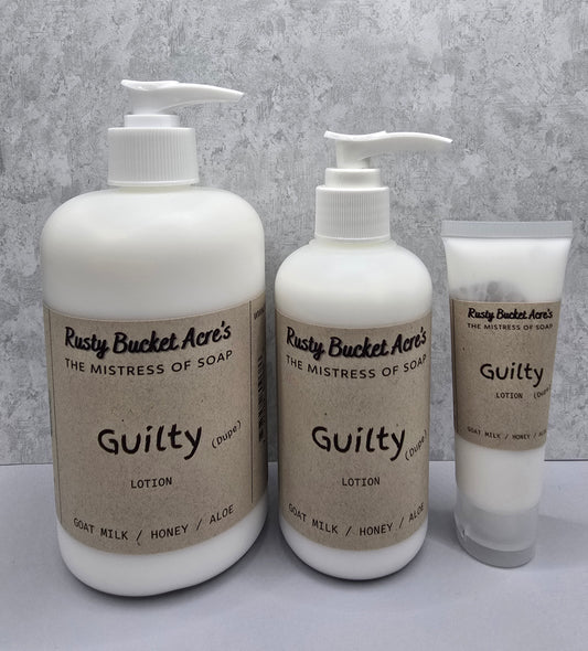 Two bottles and a tube of Rusty Bucket Acres Guilty Dupe lotion on a gray background