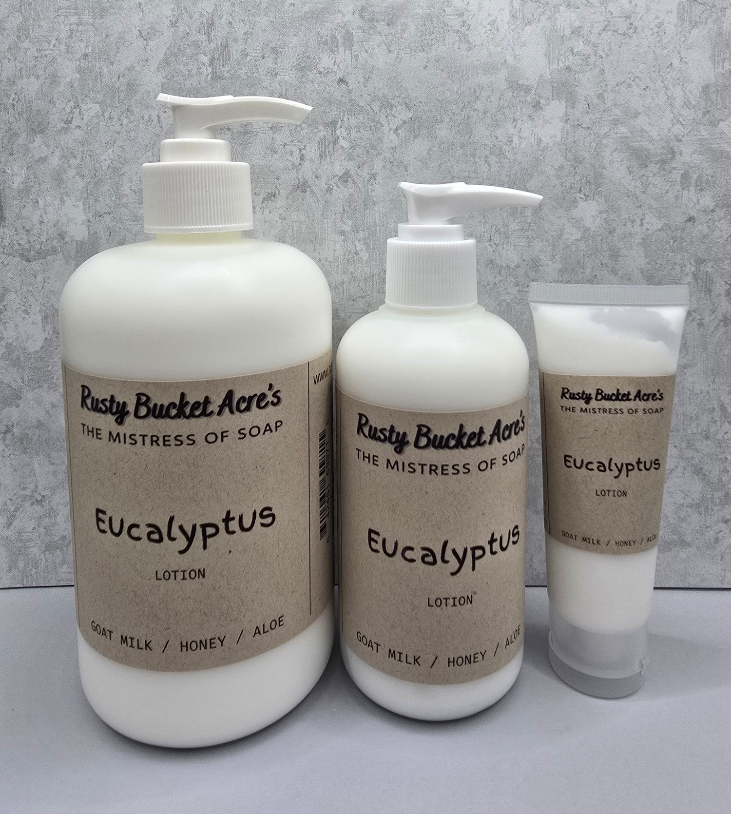 Two bottles and a tube of Rusty Bucket Acres Eucalyptus lotion on a gray background
