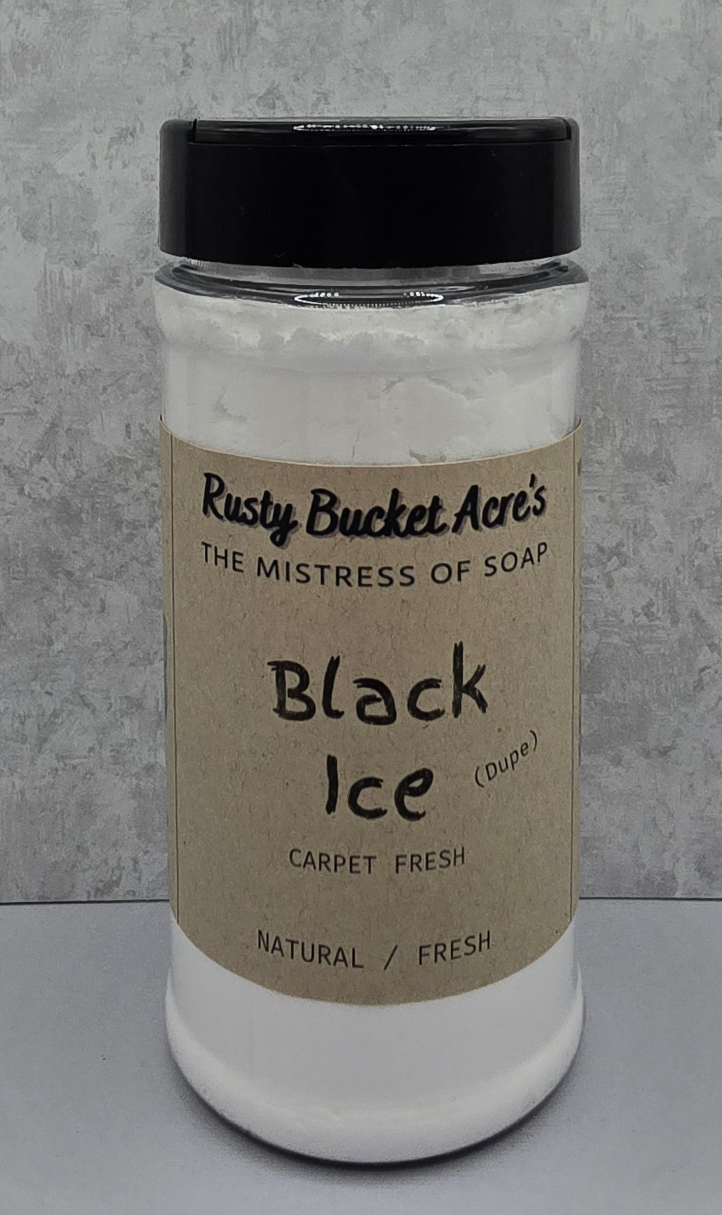 A clear plastic jar of Rusty Bucket Acre's 'Black Ice' carpet fresh soap, filled with white lather and topped with a black lid, set against a gray textured background.