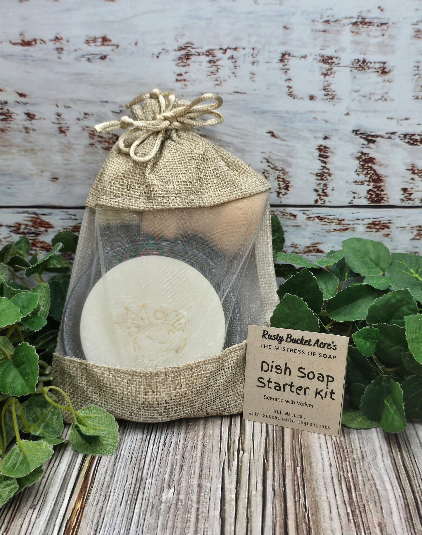 Dish soap starter kit in a burlap bag with a label on a wooden surface with greenery.