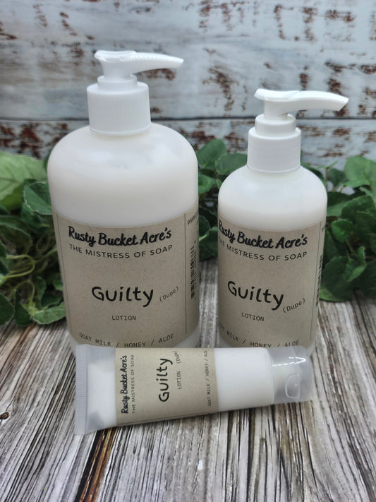 Three bottles of 'Guilty' products on a wooden surface with green leaves.