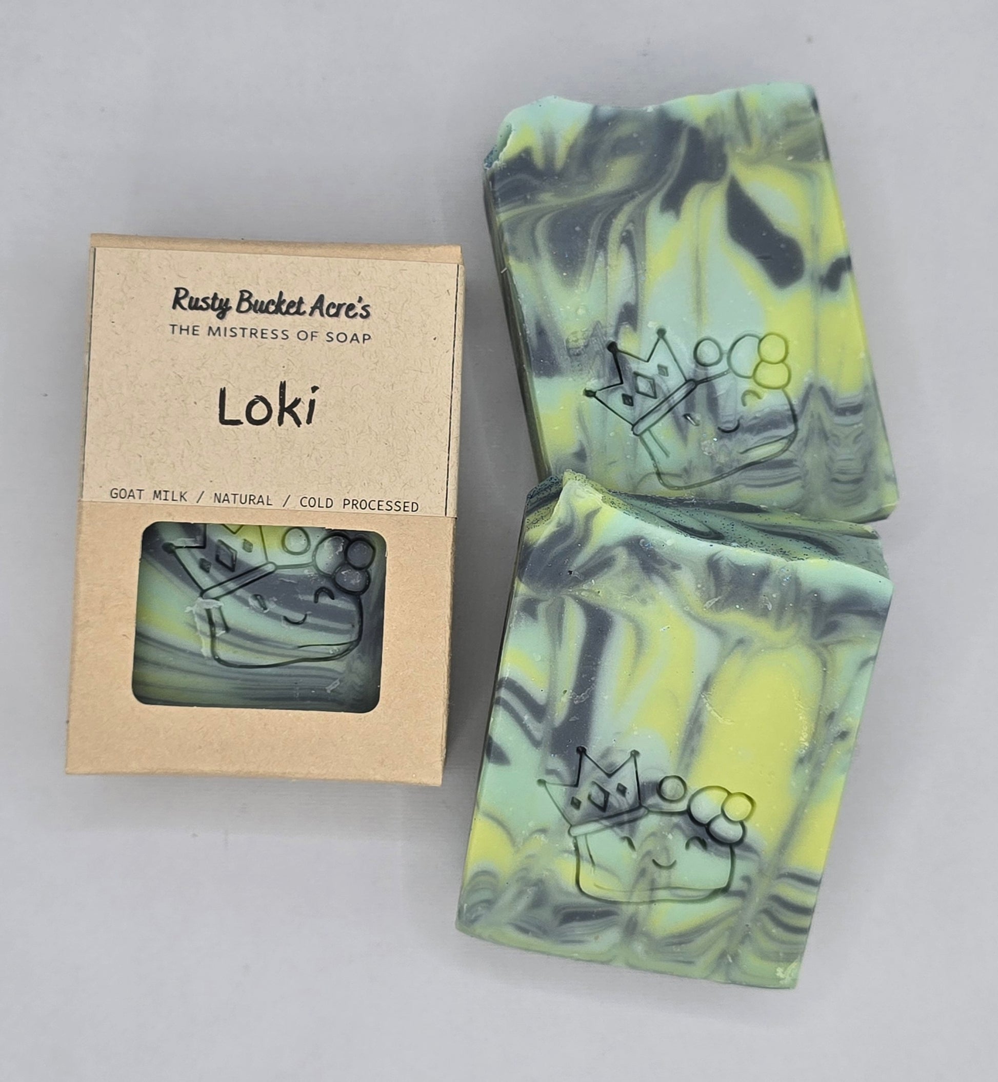 Loki artisan soap bars with a crown and a swirl design, shown next to their kraft paper packaging box labeled 'Rusty Bucket Acre's Loki'.