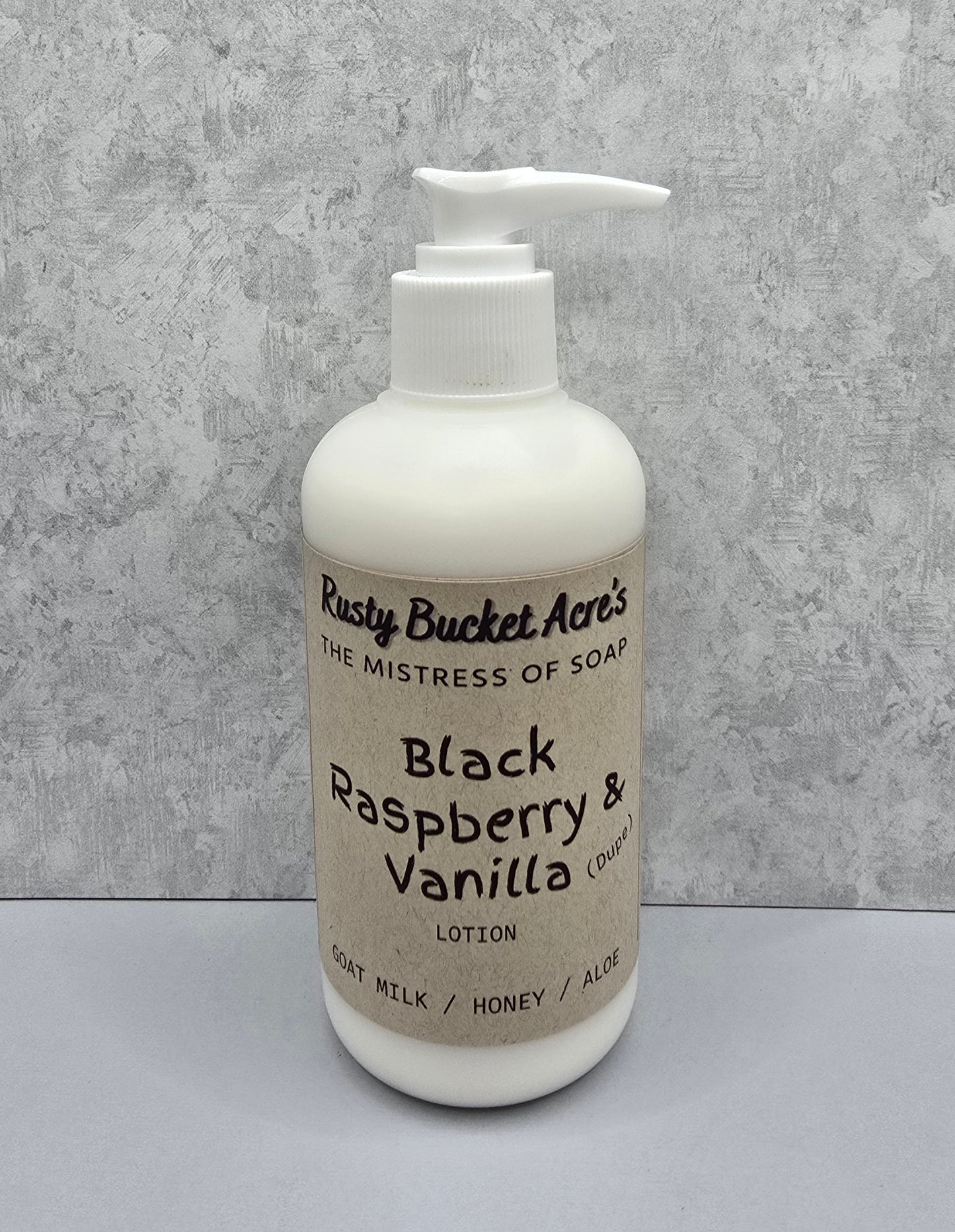 Lotion bottle with 'Rusty Bucket Acres Black Raspberry Vanilla Dupe' label on a gray background
